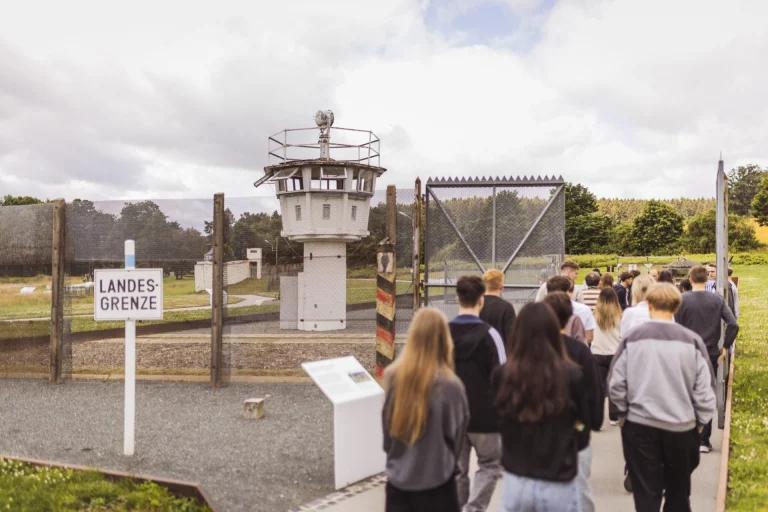 Jugendliche gehen am Wachturm und Grenzzaun entlang zum Museum Mödlareuth