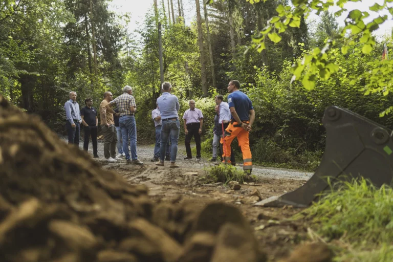 Gruppe von Personen bespricht sich am Saaleradweg neben Baggerschaufel und Erdaushub