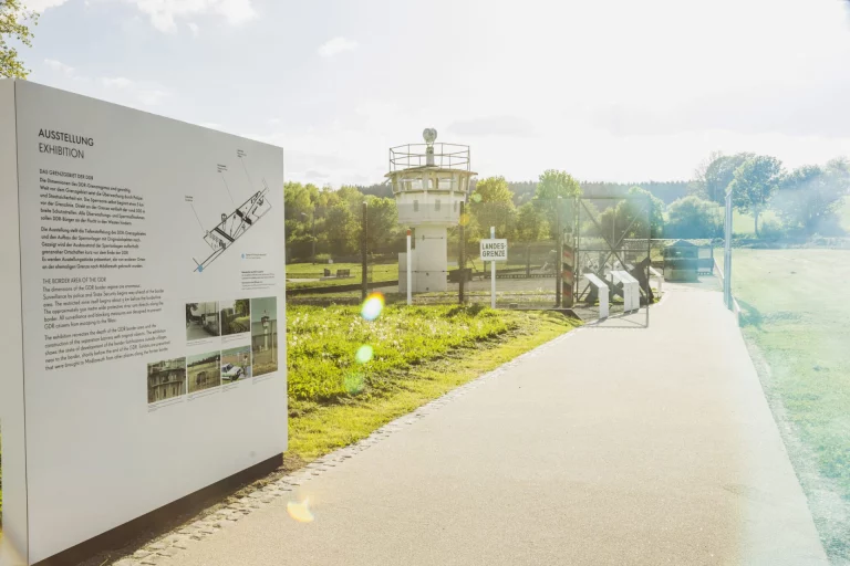 Infotafel zur Ausstellung über das DDR-Grenzregime mit Wachturm und Grenzanlagen in Mödlareuth