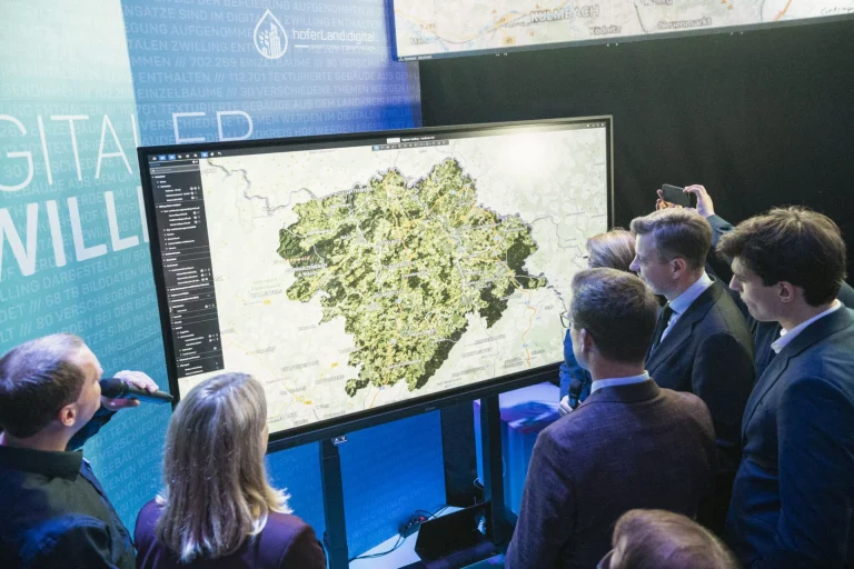 Personengruppe betrachtet digitale Gelände- und Gebäudekarte des Landkreises Hof auf Großbildschirm