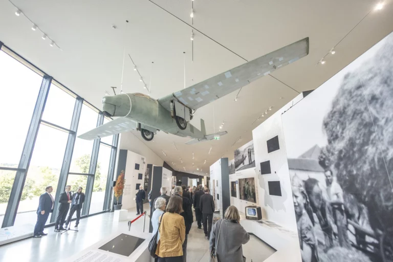 Besuchergruppe betrachtet historisches Fluggerät und Ausstellungstafeln zur deutsch-deutschen Grenzgeschichte
