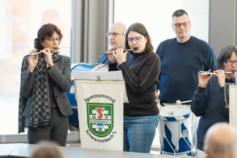 Musikerinnen und Musiker spielen Querflöte bei Feier mit Banner des Spielmannszugs Schwarzenbach