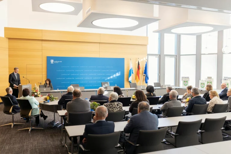Rednerpult mit Ansprache vor sitzendem Publikum im Sitzungssaal des Landratsamts