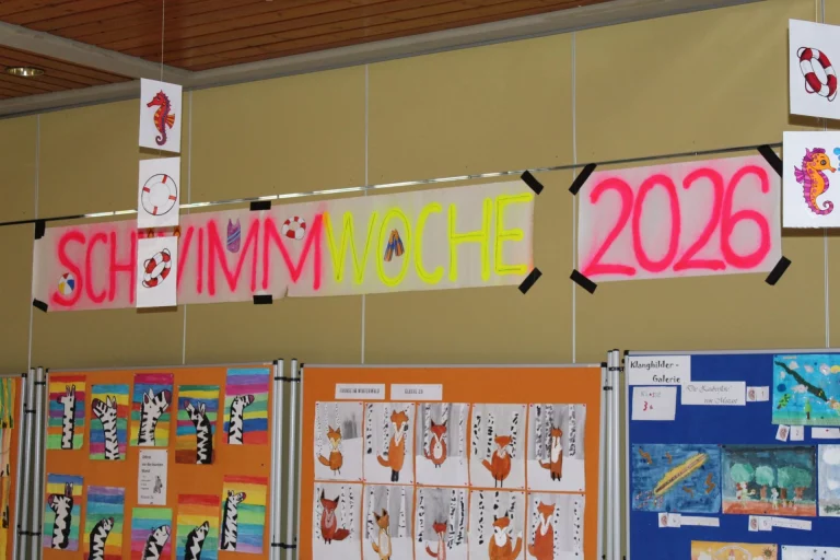 Banner „Schwimmwoche 2026“ über Schülerarbeiten mit Tier- und Fantasiemotiven in der Grundschule