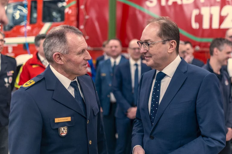 Feuerwehrmann in Uniform im Gespräch mit Bundesinnenminister vor Einsatzfahrzeug