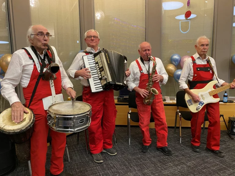 Vier Musiker in roten Faschingskostümen spielen Schlagzeug, Akkordeon, Saxofon und Bassgitarre