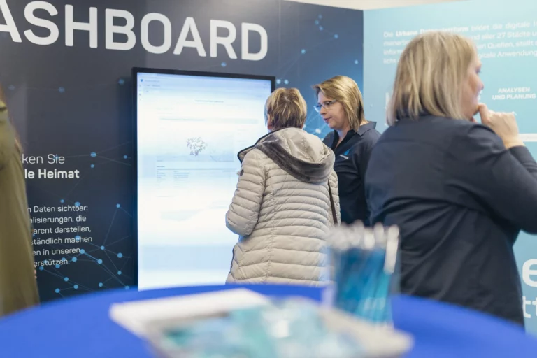 Besucherinnen informieren sich am interaktiven Dashboard-Bildschirm zu digitalen Daten der Heimat