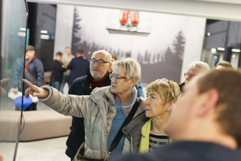 Besuchergruppe betrachtet digitale Anzeige mit Bild einer Seilbahngondel im InnovationsRAUM