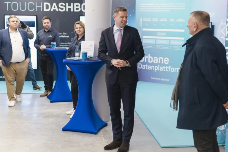 Landrat begrüßt Gäste vor Infowänden zur Urbanen Datenplattform beim InnovationsRAUM Hofer Land