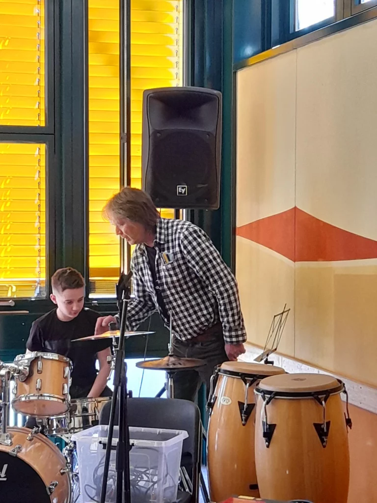 Mann und Junge stehen an Schlagzeug und Congas bei einem Bandcoaching