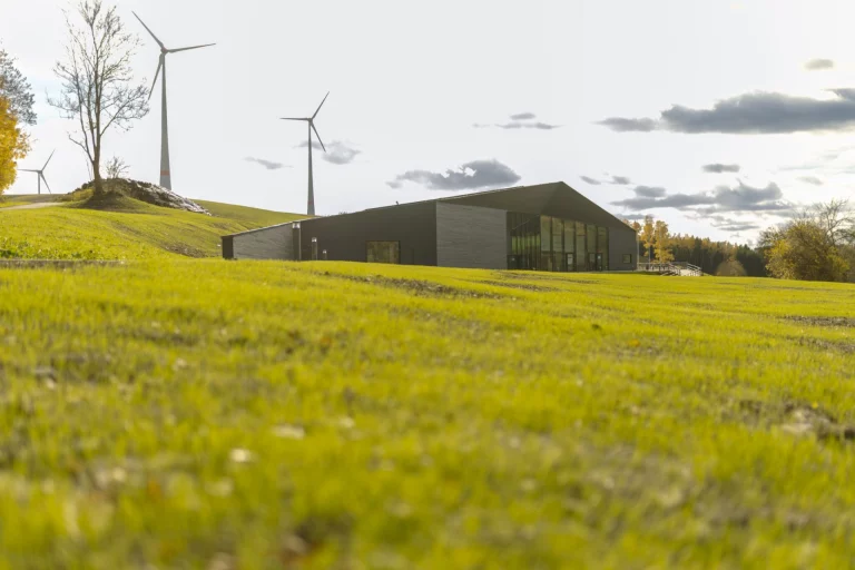 Gebäude mit begrüntem Dach und Windrädern auf einer Wiese bei Mödlareuth