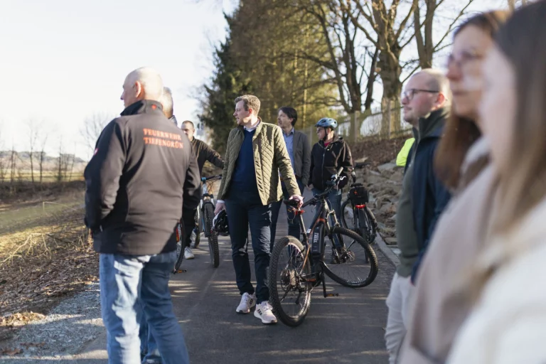 Teilnehmer schieben Fahrräder auf asphaltiertem Weg bei der Einweihung des Flüsseradweg-Abschnitts