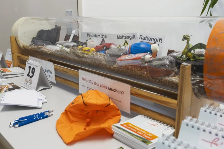 Vitrine mit gesundheitsschädlichen Stoffen und Warnhinweis „Willst Du das alles rauchen?“