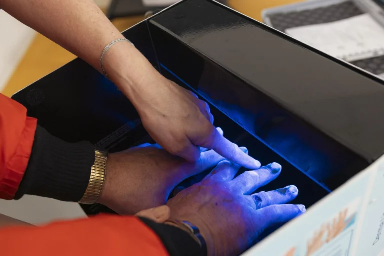 Hände unter UV-Licht zur Kontrolle der Händehygiene an einem Infostand