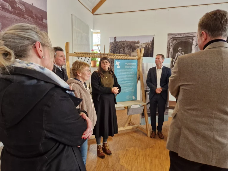 Besuchergruppe mit Museumsmitarbeiterin vor Ausstellungstafeln und historischen Fotografien im Bauernhofmuseum