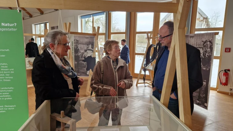 Zwei Frauen und ein Mann im Gespräch an einer Vitrine in der Museumsausstellung