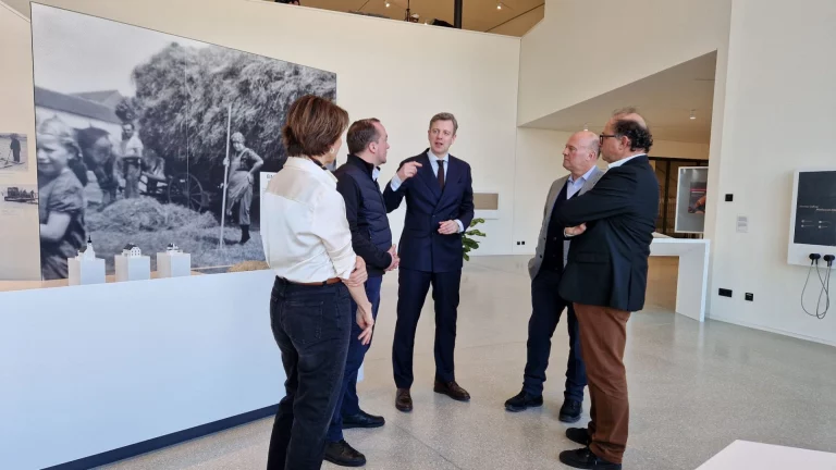 Gruppe von Personen im Gespräch vor historischer Fotoausstellung im Deutsch-Deutschen Museum
