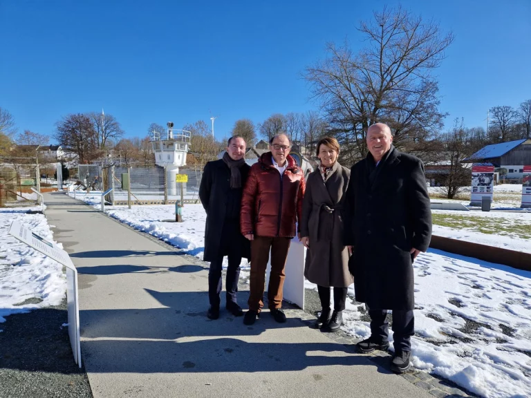 Vier Personen stehen am Deutsch-Deutschen Museum vor einem ehemaligen Grenzwachturm im Schnee