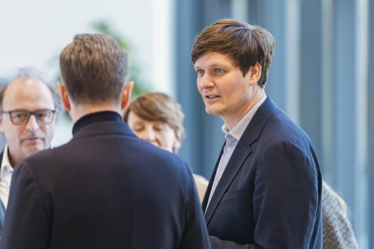 Mann im Gespräch mit mehreren Personen in einem Foyer