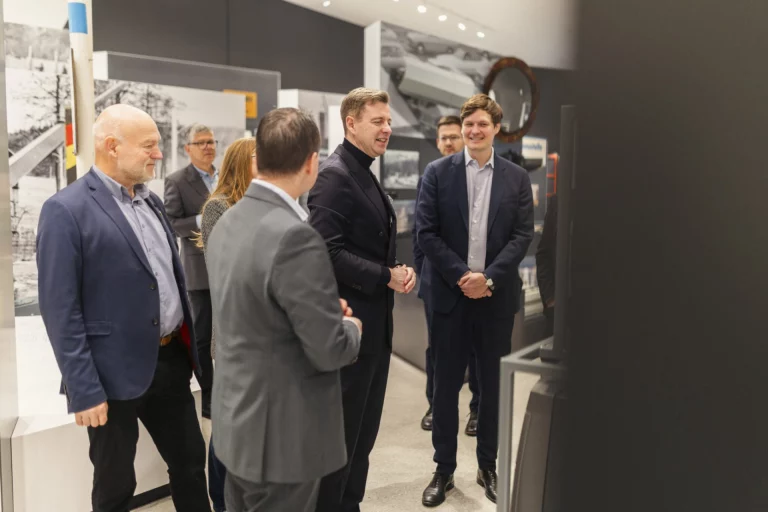 Gruppe von Personen im Gespräch vor historischen Fotografien in der Museumsausstellung