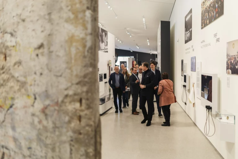 Besuchergruppe in Ausstellungsraum des Museums Mödlareuth, im Vordergrund ein Mauerrest