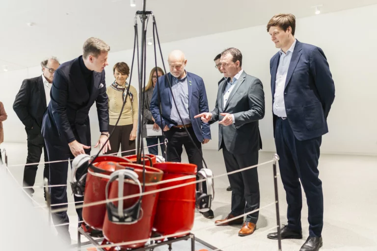 Besuchergruppe betrachtet rote Behälterkonstruktion in der Ausstellung