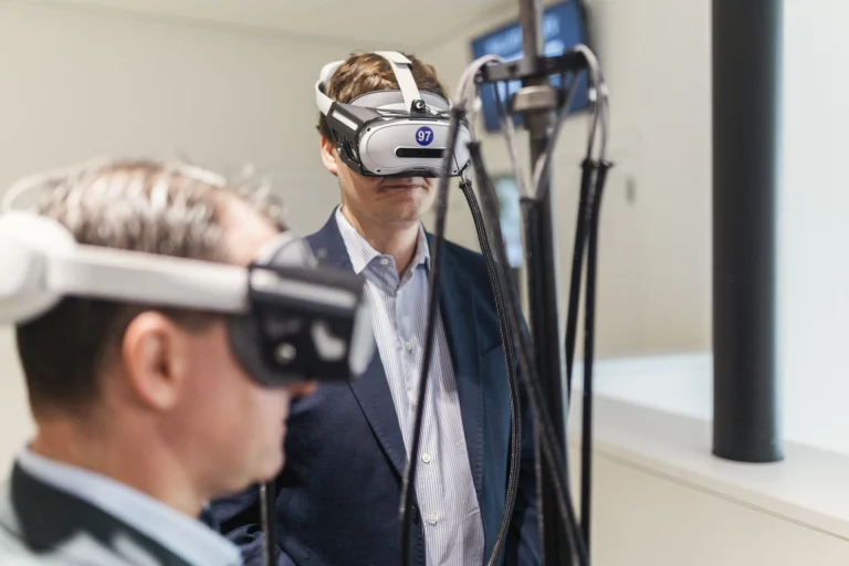 Zwei Männer mit VR-Headset und Kabelverbindungen zu Messgeräten