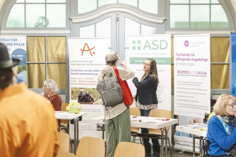 Informationsmesse mit Ständen zu Demenz und Angehörigenberatung, Besucher im Gespräch