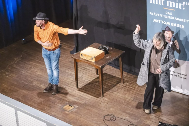 Szene aus dem Präventionskabarett „Ned mit mir!“ mit zwei Darstellern und einer Zuschauerin auf der Bühne