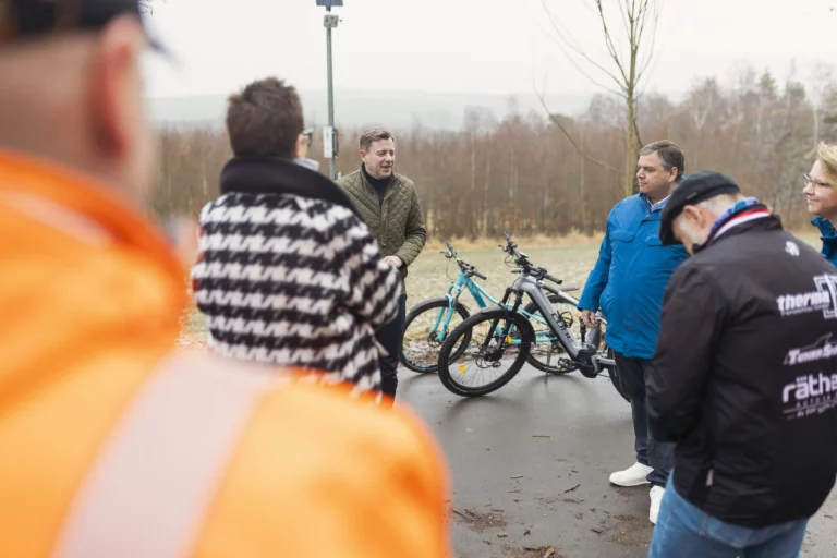 Gruppe von Personen mit E-Bikes bespricht sich auf einem Radweg im Freien