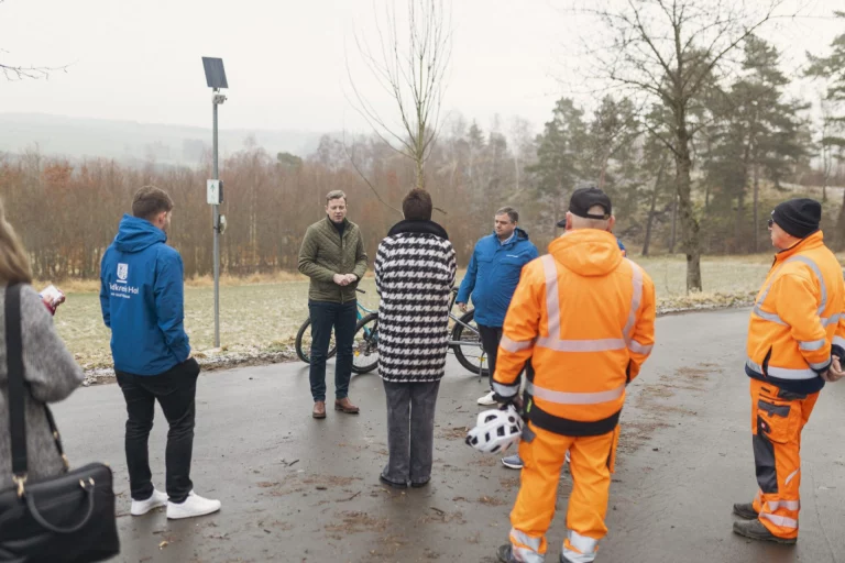 Gruppe mit Fahrrädern und Warnkleidung steht an Messstation am Radweg