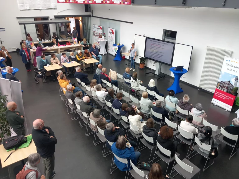 Vortragender vor Präsentation, Publikum auf Stuhlreihen, Roll-up „Seniorenrat Stadt Hof“