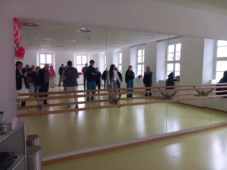 Gruppe von Personen vor einer Spiegelwand mit Ballett-Handlauf im Gymnastikraum