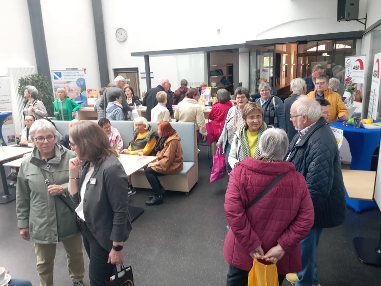 Besucherinnen und Besucher im Gespräch an Infoständen zur Präventionsarbeit im Foyer