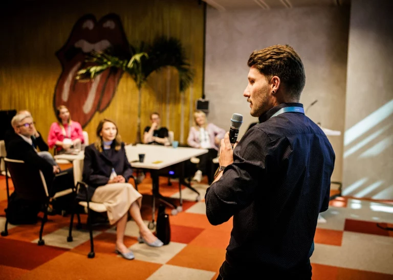 Mann mit Mikrofon spricht zu Podiumsgast und Publikum beim MPSC-Kongress