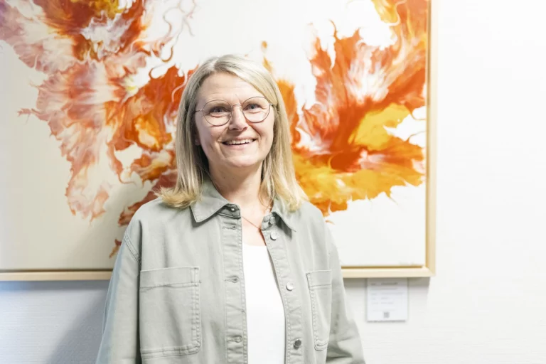 Frau mit Brille vor orangefarbenem abstrakten Acrylgemälde