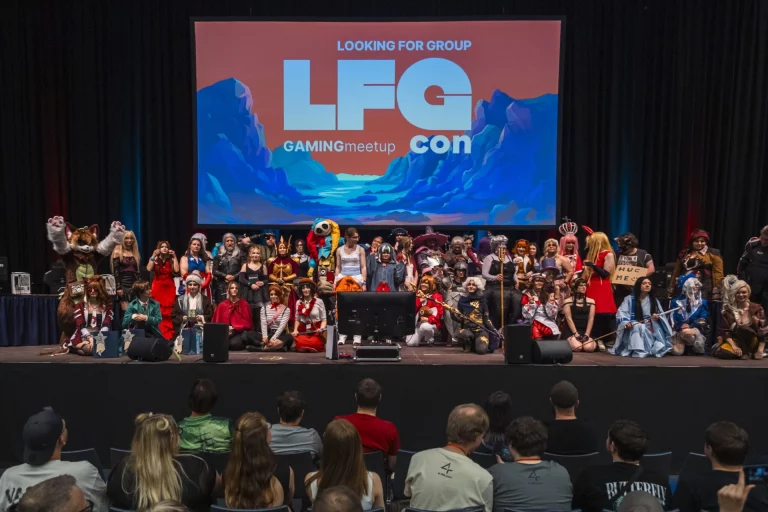 Cosplay-Gruppe auf Bühne vor Leinwand mit Aufschrift „LFG Con“, davor sitzendes Publikum