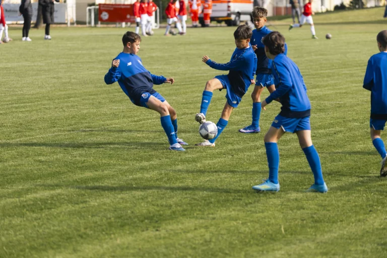 Jugendliche in blauen Trikots beim Zweikampf um den Ball auf dem Fußballplatz