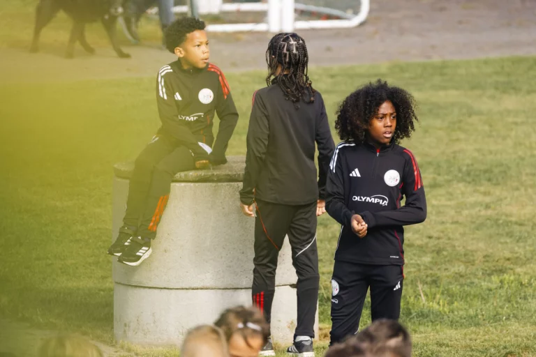 Jugendliche in Sportkleidung mit Vereinslogo auf dem Rasen vor einem Fußballtor