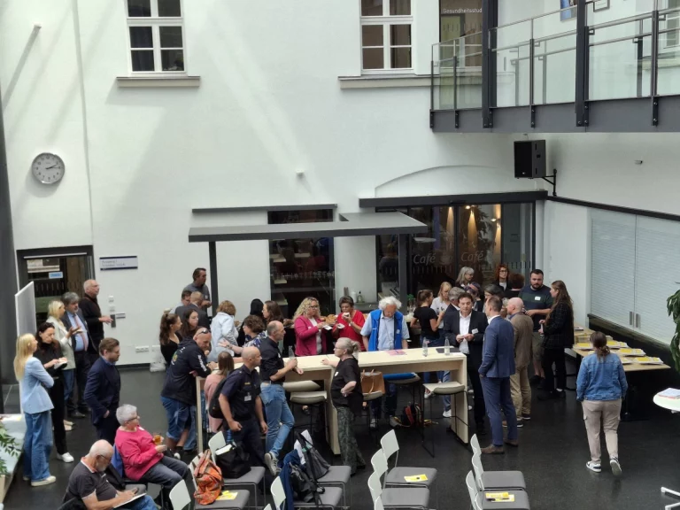 Innenhof mit Menschengruppen im Gespräch an Stehtischen bei der Präventionskonferenz