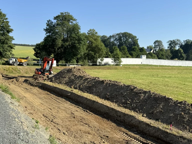 Bagger hebt Graben für neuen Gehweg entlang der Kreisstraße am Feldrand aus