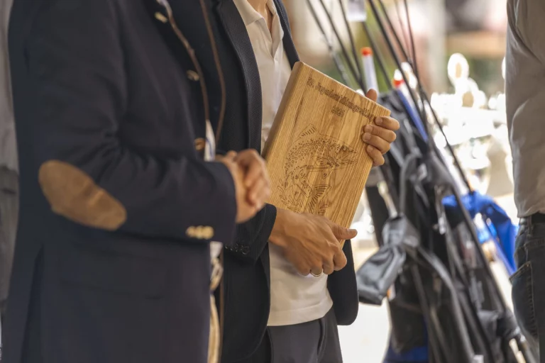 Person überreicht eine gravierte Holzplakette im Rahmen des Jugendausbildungszeltlagers