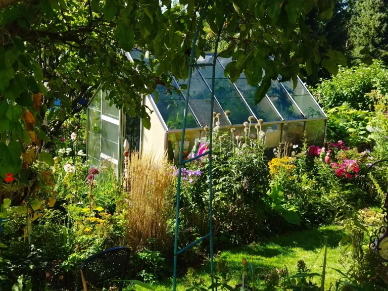 Gewächshaus und blühende Beete in einem Hofer Garten entlang der Radtour