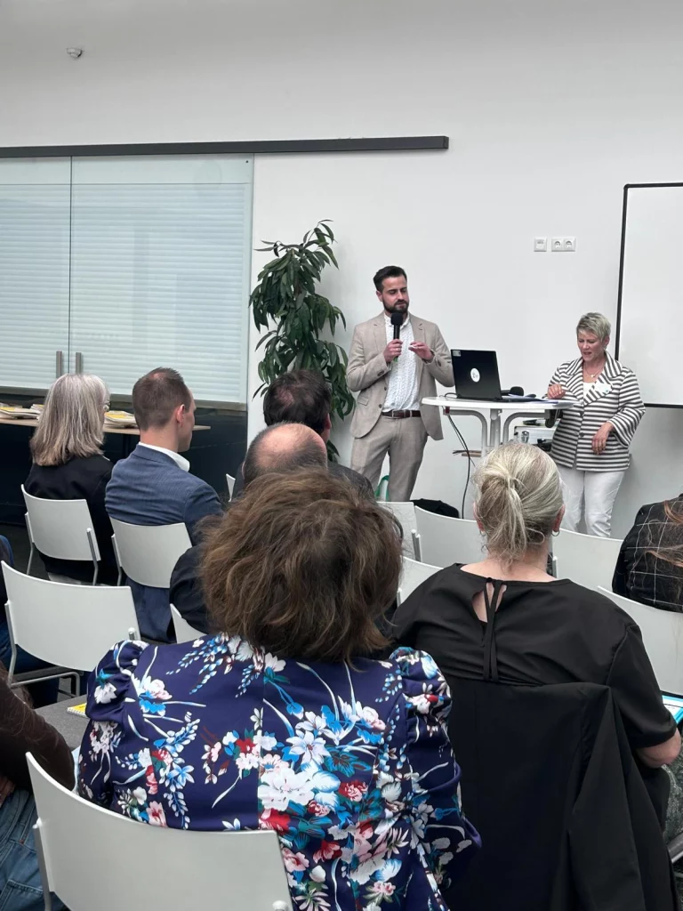 Mann mit Mikrofon und Frau am Stehtisch vor Publikum bei der Präventionskonferenz