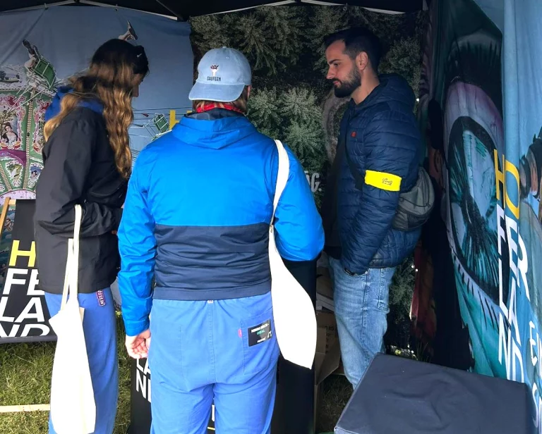 Personen im Gespräch am Infostand des Hofer Landes mit Planen und Taschen