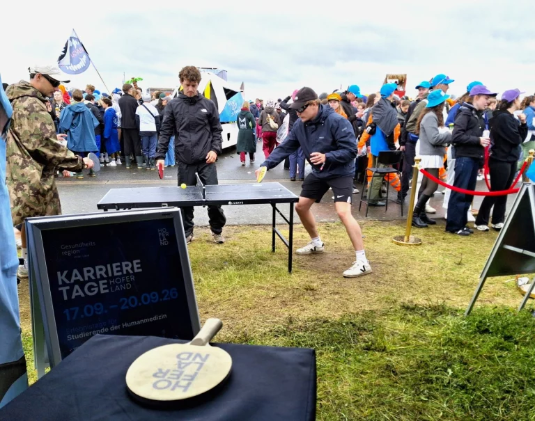 Tischtennis vor Infotafel „Karrieretage Hofer Land“ bei Veranstaltung mit vielen Besuchenden