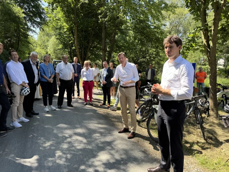 Gruppe von Personen mit Fahrrädern bei der Einweihung des Flüsseradwegs im Wald