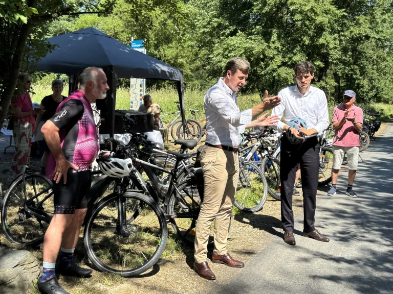 Zwei Männer mit Fahrradhelm im Gespräch neben abgestellten Fahrrädern am Flüsseradweg