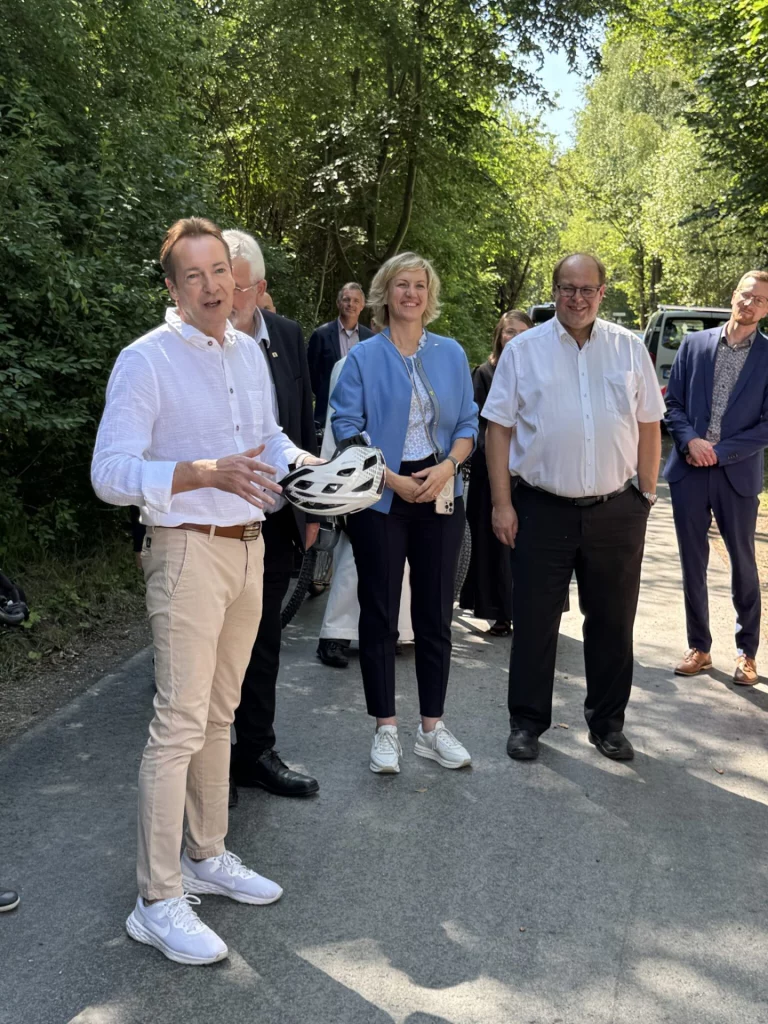 Mann mit Fahrradhelm im Gespräch mit einer Gruppe von Personen auf dem Flüsseradweg