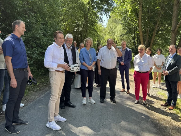 Gruppe von Personen bei der Einweihung eines Abschnitts des Flüsseradwegs auf einem Waldweg